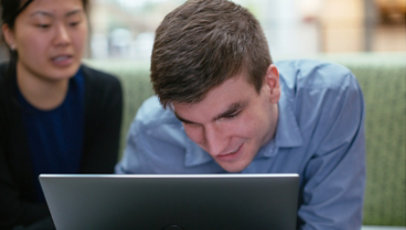 A man who has low vision looks closely at the screen on a laptop.