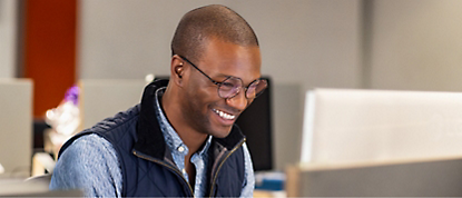 Um homem está sorrindo enquanto trabalha em um computador
