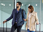 Ένας άνδρας και μια γυναίκα με αποσκευές σε ένα αεροδρόμιο.