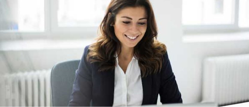 En kvinne som sitter og smiler på et kontor