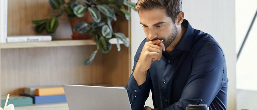En mand, der sidder ved et skrivebord med en bærbar computer foran sig.
