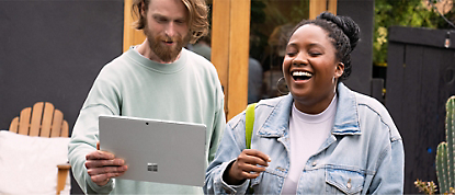 一名男士和女士拿著 Microsoft Surface 平板電腦大笑。