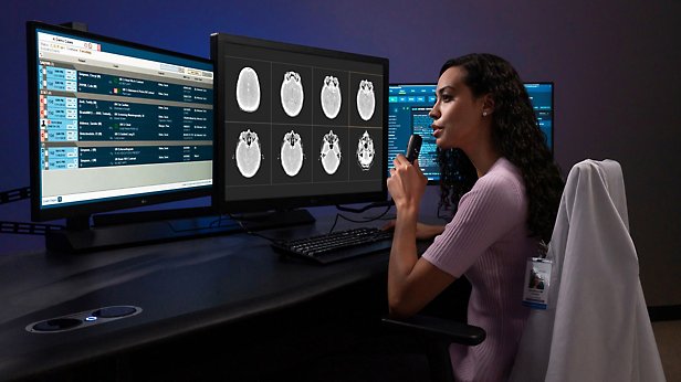Osoba z wieloma monitorami, spoglądająca na dane wyświetlane na ekranie i analizująca je.