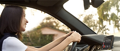 Una mujer conduce un coche con las manos en el volante.
