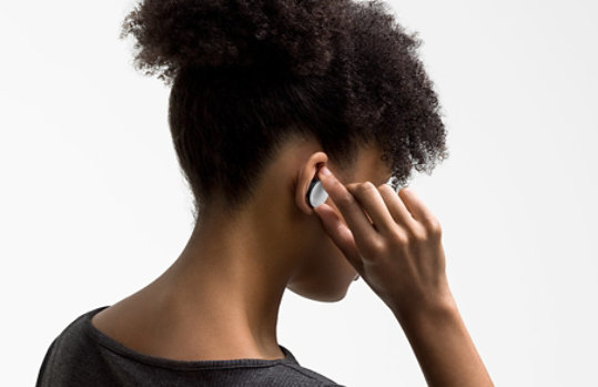 A woman adjusts the volume of her Surface Earbuds.