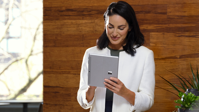 서서 태블릿 모드의 Surface Go 4에 필기를 하는 여성