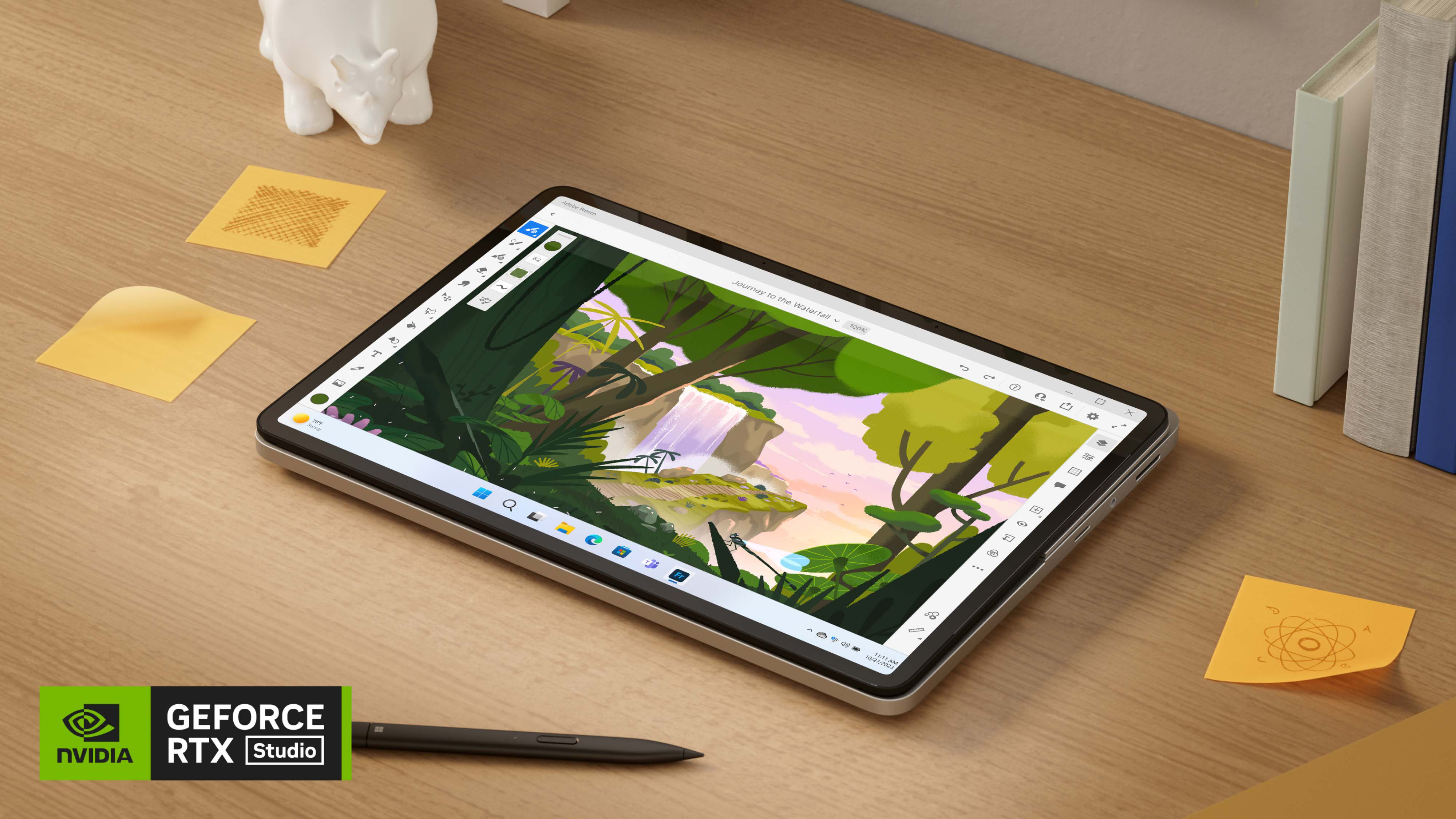 Surface Laptop Studio 2 ในโหมดแท็บเล็ตข้าง ๆ Surface Slim Pen 2 และกระดาษโน้ตบนโต๊ะไม้