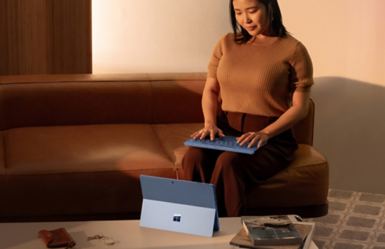 A seated person using Surface Pro Sapphire with detached keyboard.