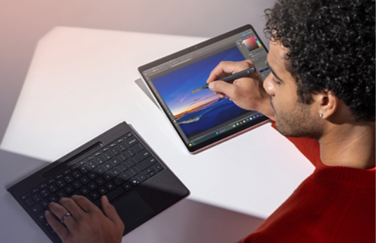 Een persoon gebruikt een losgekoppelde Surface Pro Flex Keyboard en Slim Pen om een foto op Surface Pro te bewerken.