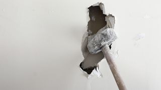 A sledgehammer smashing through a white wall