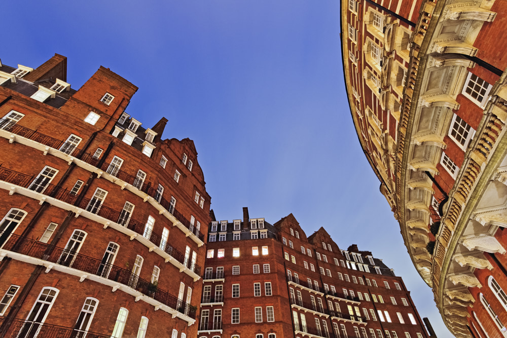 upwards view of red brick curved buildings against blue sky
