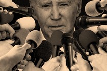 Biden surrounded by hands extending microphones