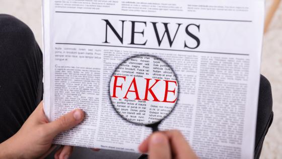 Man Examining Fake News On Newspaper