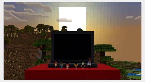 Rendered in-game in Minecraft, a table with a laptop on it. In front of the laptop are Minecraft characters.