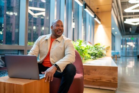Daryl Hammett, GM of Global Demand Generation and Operations, works on his laptop in an AWS office and smiles at an onlooker.