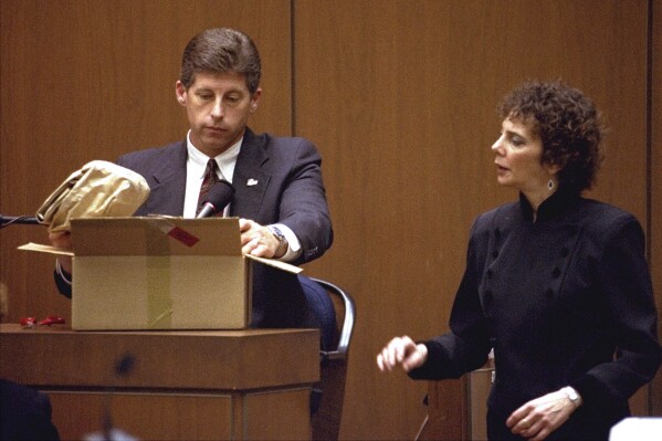 FILE - Los Angeles Police Detective Mark Fuhrman shows the jury in the O.J. Simpson double murder trial evidence during testimony Friday, March 10, 1995, in Los Angeles. Fuhrman, 72, who was convicted of lying on the witness stand in the O.J. Simpson trial three decades ago, is now barred from law enforcement under a California police reform law meant to strip the badges of police officers who act criminally or with bias. (AP Photo/Nick Ut, Pool, File)