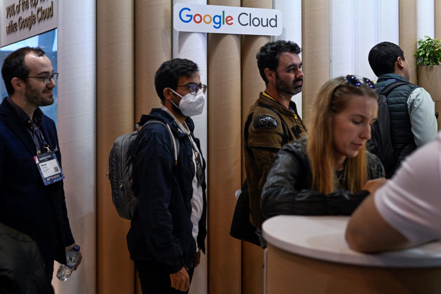 A group of people wait in a line underneath a Google Cloud sign in Lisbon, Portugal.