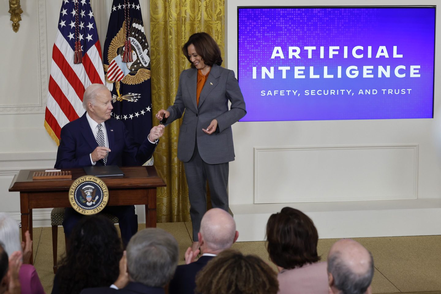 WASHINGTON, DC &#8211; OCTOBER 30: U.S. President Joe Biden hands Vice President Kamala Harris the pen he used to sign a new executive order regarding artificial intelligence during an event in the East Room of the White House on October 30, 2023 in Washington, DC. President Biden issued the executive order directing his administration to create a new chief AI officer, track companies developing the most powerful AI systems, adopt stronger privacy policies and &#8220;both deploy AI and guard against its possible bias,&#8221; creating new safety guidelines and industry standards. (Photo by Chip Somodevilla/Getty Images)