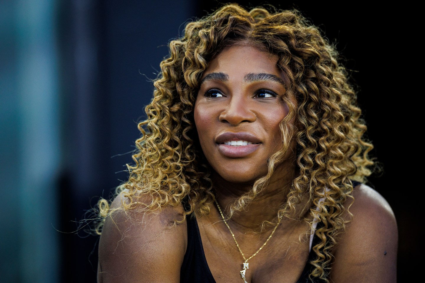 Portrait of Serena Williams wearing a necklace that says "Mama" while watching a match.