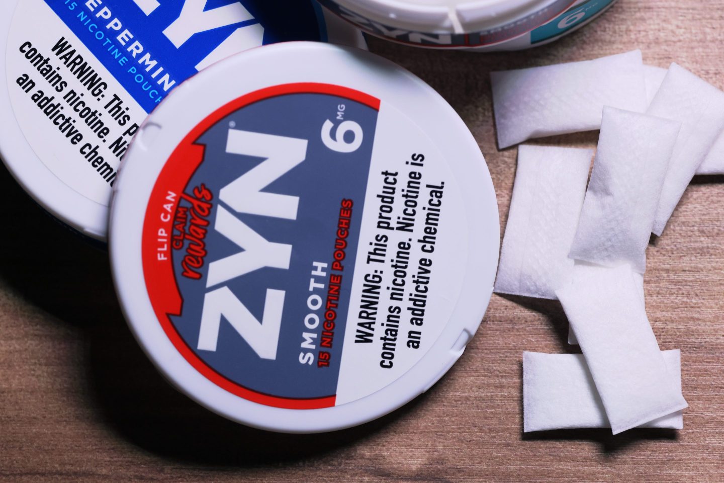 white Zyn nicotine pouches next to round can labeled "Zyn"