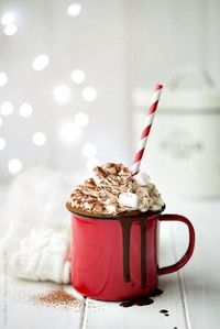 Hot cocoa with mini marshmallows, drizzled with chocolate syrup dripping over edge, maybe some sprinkles, on a blank surface where dripping chocolate is visible.
