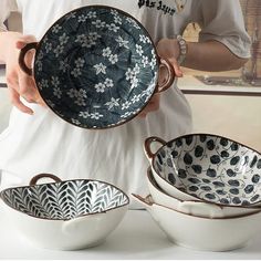 a person is holding three bowls in their hands and one bowl has an ornate design on it