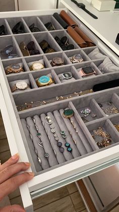 a person is holding an open drawer full of jewelry