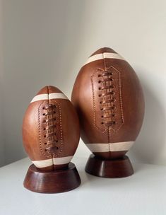 two brown leather footballs sitting on top of each other