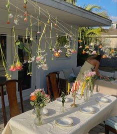 an outdoor dining area with flowers and candles hanging from the rafters over the table