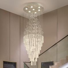 a chandelier hanging from the ceiling in a living room next to some stairs