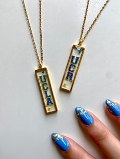 two necklaces with blue and gold designs on them, one has a name tag