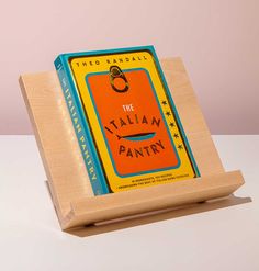 the italian pantry book is sitting on a wooden stand with an orange tag hanging from it's cover