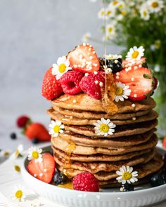 a stack of pancakes topped with strawberries and syrup