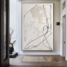 an abstract painting hangs on the wall above a rug in a room with hardwood floors