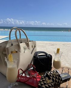 a handbag and purse sitting on top of a wooden table next to the ocean