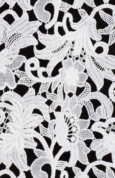 white lace on black fabric with flowers and leaves in the center, close up photo