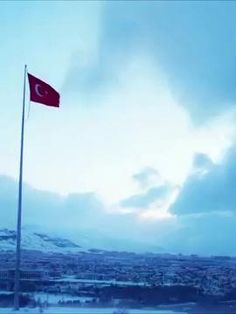 a red flag flying high in the sky over a snow covered mountain range with clouds
