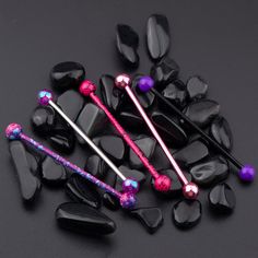 some black rocks and purple beads on top of each other with one pink bead in the middle