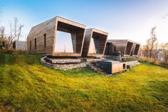 the building is made out of wood and sits on top of a grassy hill near water