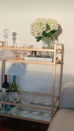 a gold bar cart with wine glasses and bottles on it