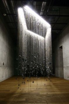 an art installation made out of metal rods and strings in a large room with wooden floors