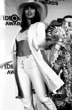 an old photo of a woman in white pants and a hat on the red carpet