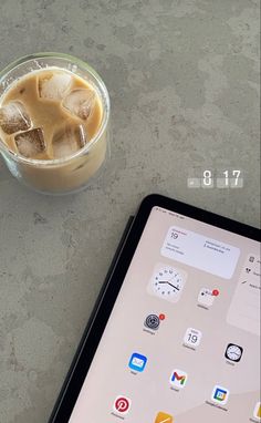 an ipad next to a drink on a table