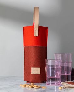 a red bag sitting on top of a counter next to two glasses and a cup