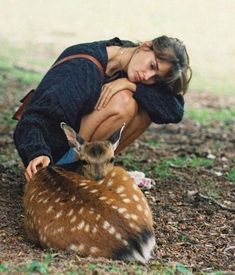 a woman kneeling down next to a deer
