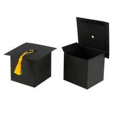 two black boxes with yellow tassels and a graduation cap in the top one