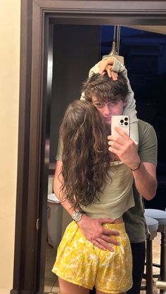 a man and woman taking a selfie in front of a mirror with their arms around each other