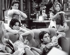 three people sitting on a couch in a living room with one person holding his leg up