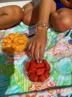 a woman is sitting at a table with some fruit in bowls on it and her hands are touching the bowl