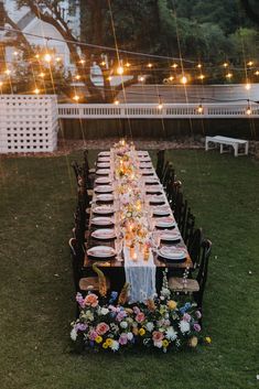 a long table set up with flowers and candles for an outdoor dinner party in the backyard
